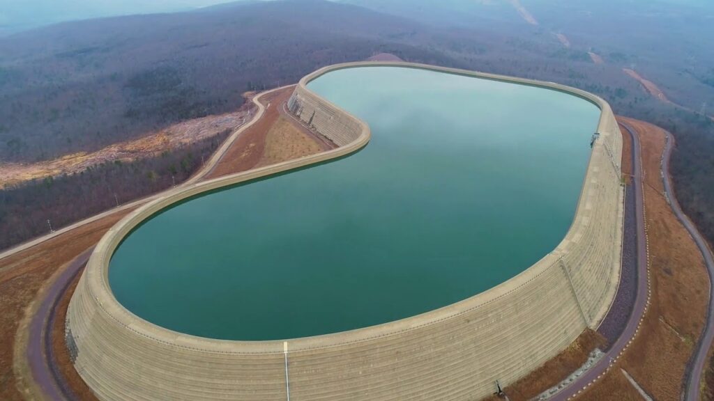Aerial view of a Pumped Storage Hydropower (PSH) plant infrastructure with upper reservoir and high-pressure penstocks.